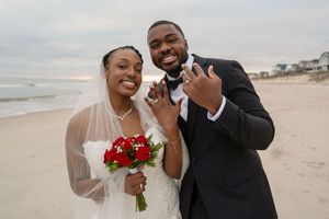 Joyful wedding couple laughing and dancing together on a scenic beach.