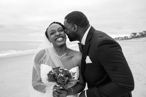 A romantic beach wedding photoshoot with a couple embracing on sandy shores at sunset.