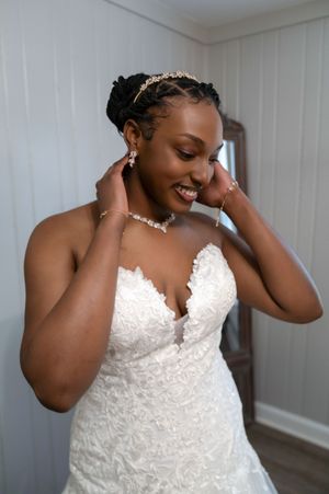 Candid moments of bride in white lace dress adjusting her veil and jewelry.