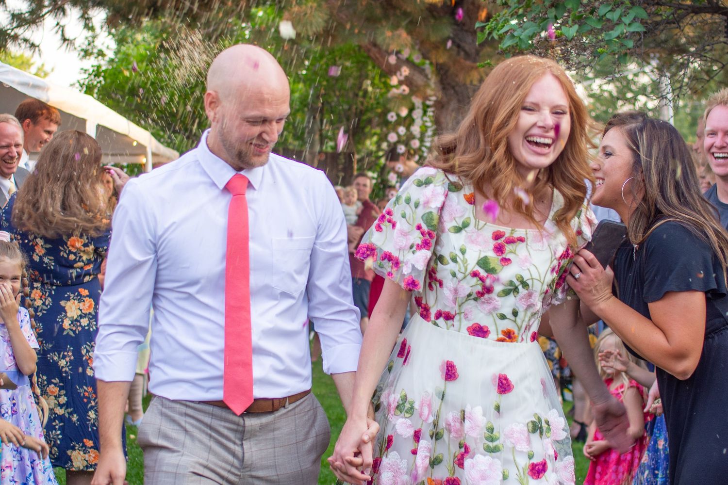 Guests enjoying a joyful outdoor celebration with confetti falling in a garden party setting.