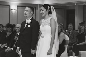 A bride and groom share a joyful moment during their wedding ceremony while guests look on in the background.