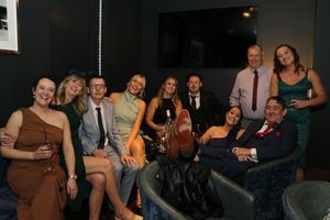 A group of people sit together on a couch at what appears to be a social gathering or party.