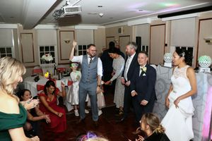 Wedding reception dance floor filled with guests celebrating at an indoor venue.