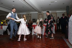 Wedding guests dancing and celebrating together on a red-carpeted dance floor at an indoor reception.