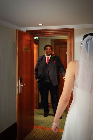 A sequence of wedding photos showing a person in a black suit and red tie entering through a wooden door.