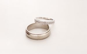 Two silver wedding bands, one plain and one diamond-encrusted, placed together on a white background.