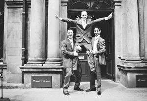 A black and white photo series showing playful moments between people on a classic building's entrance steps.