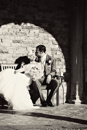 A romantic black and white photo sequence showing a couple in wedding attire sitting on a bench against a brick wall.