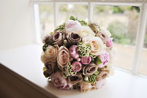 A romantic bouquet of pink and cream roses with delicate baby's breath flowers arranged for a wedding celebration.