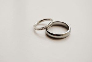 Close-up view of platinum or white gold wedding bands and engagement rings on a light neutral background.