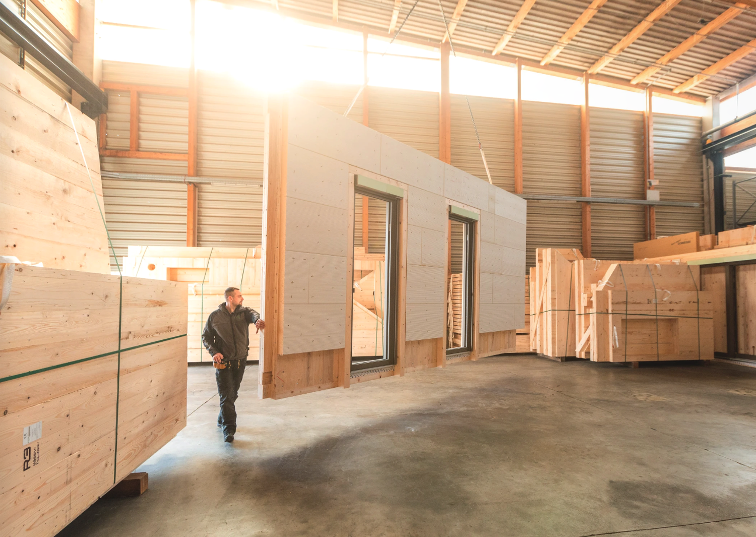 Construction workers assemble large wooden wall panels during new home construction on a sunny day.