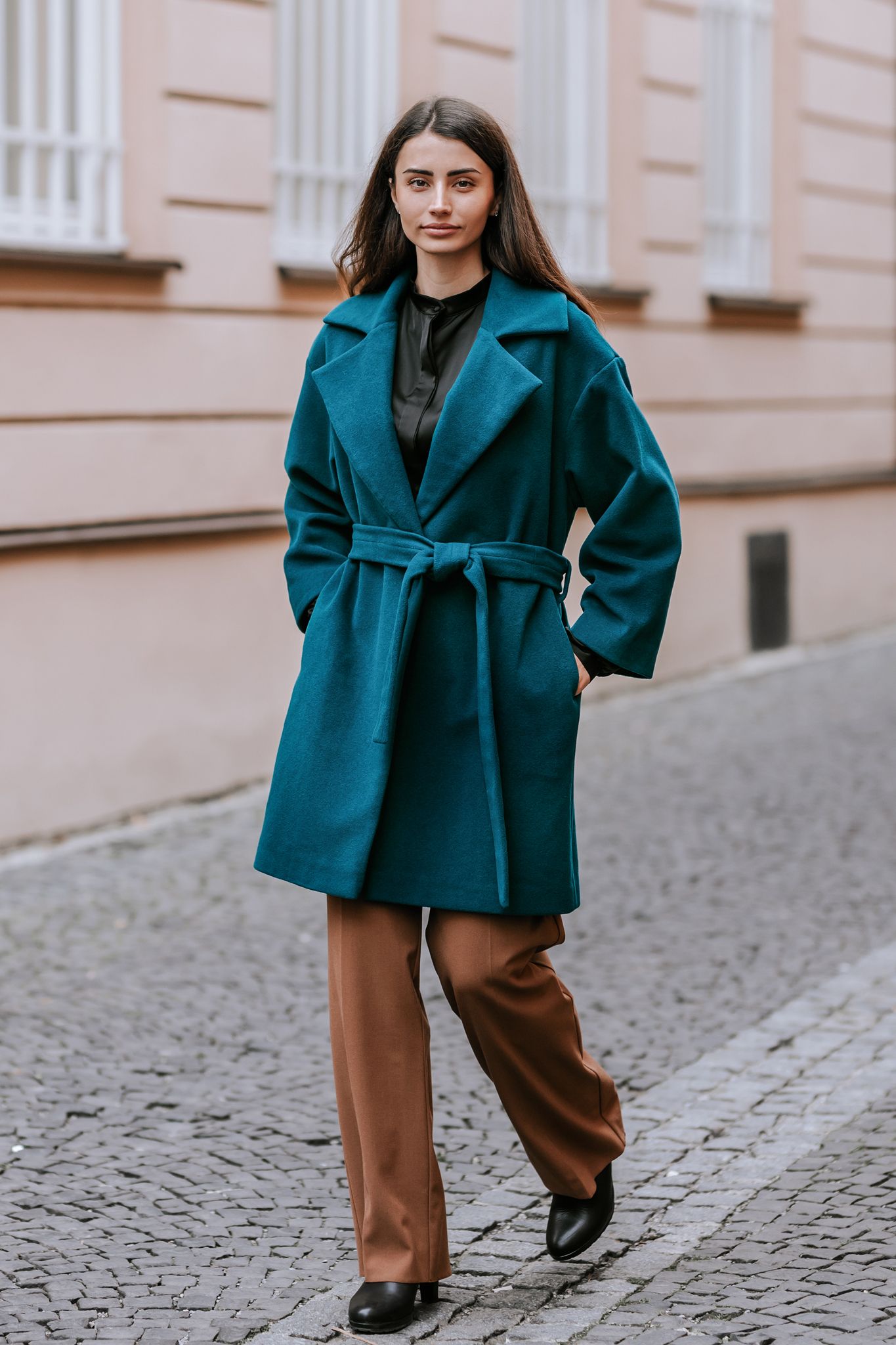 Mladá žena v elegantnom smaragdovom kabáte na mestskej ulici. Profesionálne portrétne a módne fotenie v Žiline.