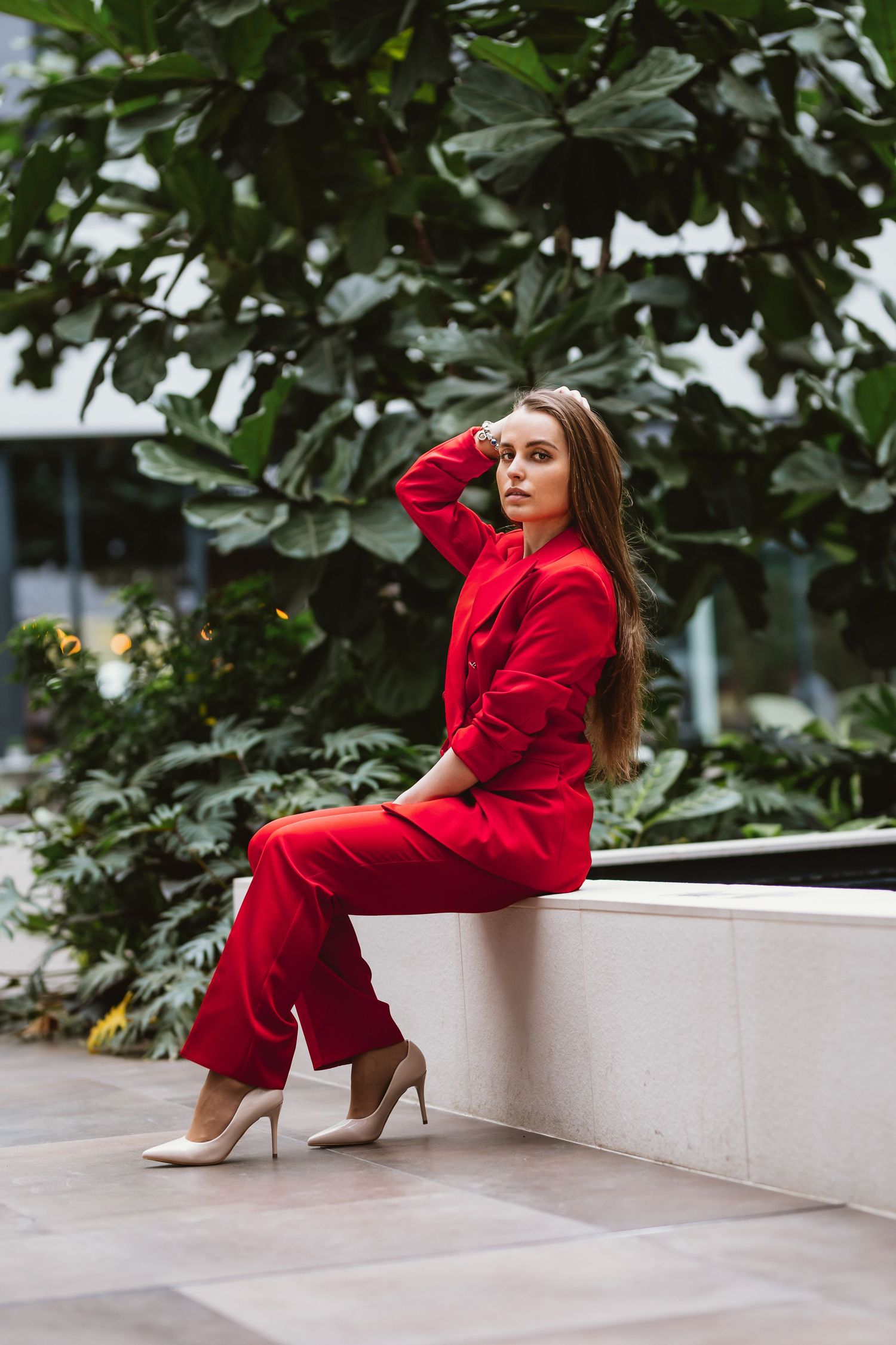 Elegantná žena v svetlom biznis kostýme kráča pred modernou presklenou budovou. Biznis portrét a street style fotografia, Žilinský kraj.