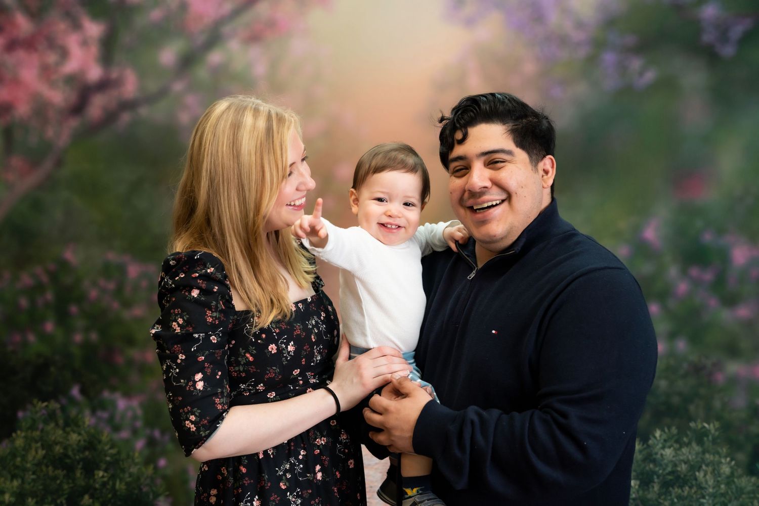 A couple embraces in a garden setting with pink cherry blossoms creating a romantic spring atmosphere.