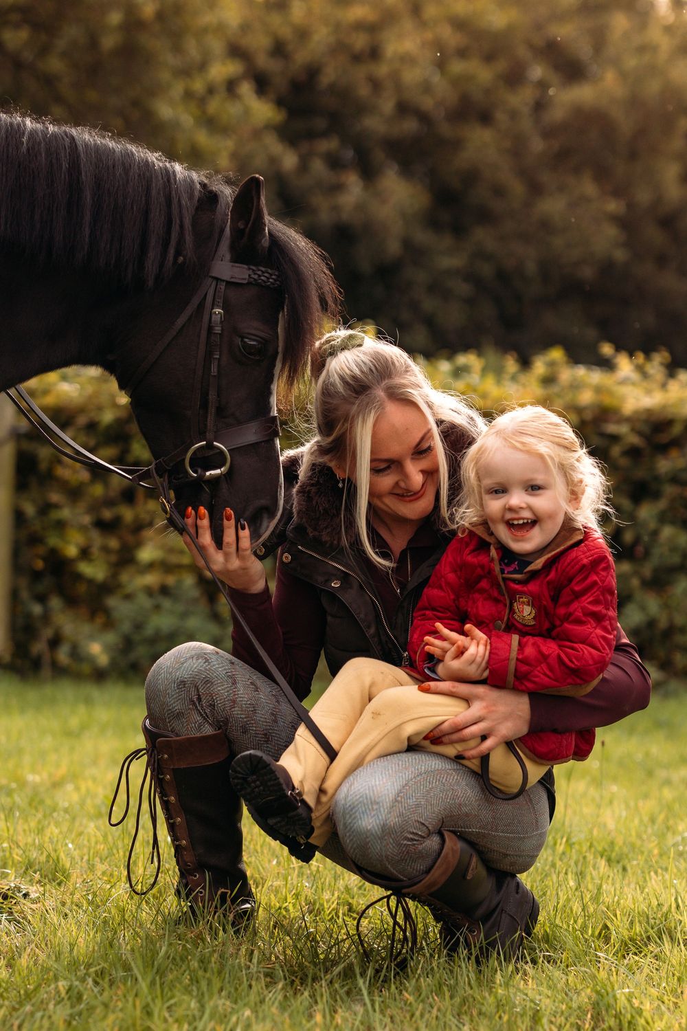 A heartwarming interaction between a dark horse and companion sharing joyful moments on grass.