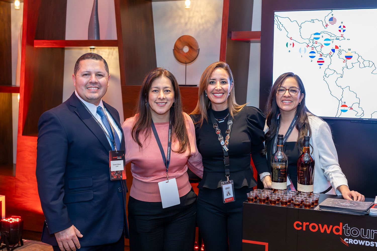 Business professionals networking and engaging in discussions at a corporate event with red lighting and branding.