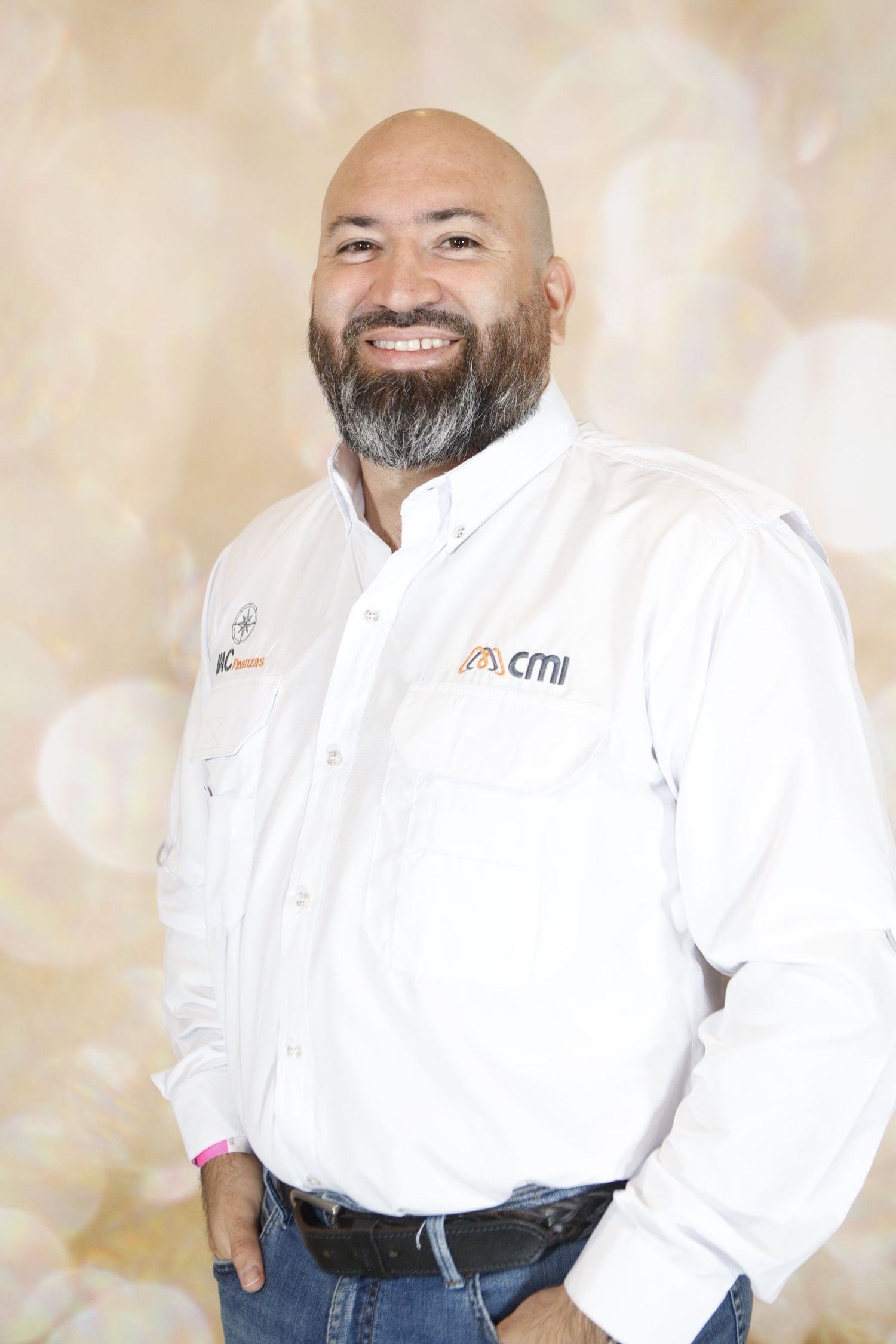 Professional portrait of someone in a white button-down shirt and jeans against a beige backdrop, showing a warm smile.
