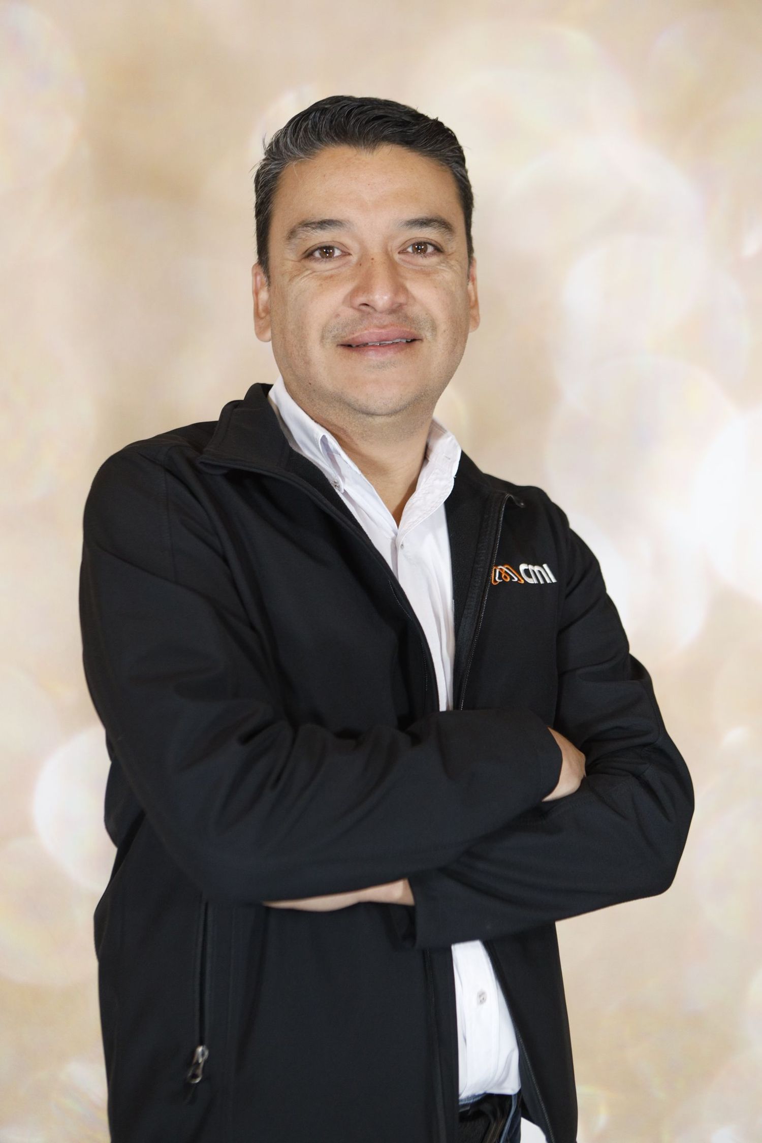 Professional business portrait of person in black jacket and white shirt against beige background.