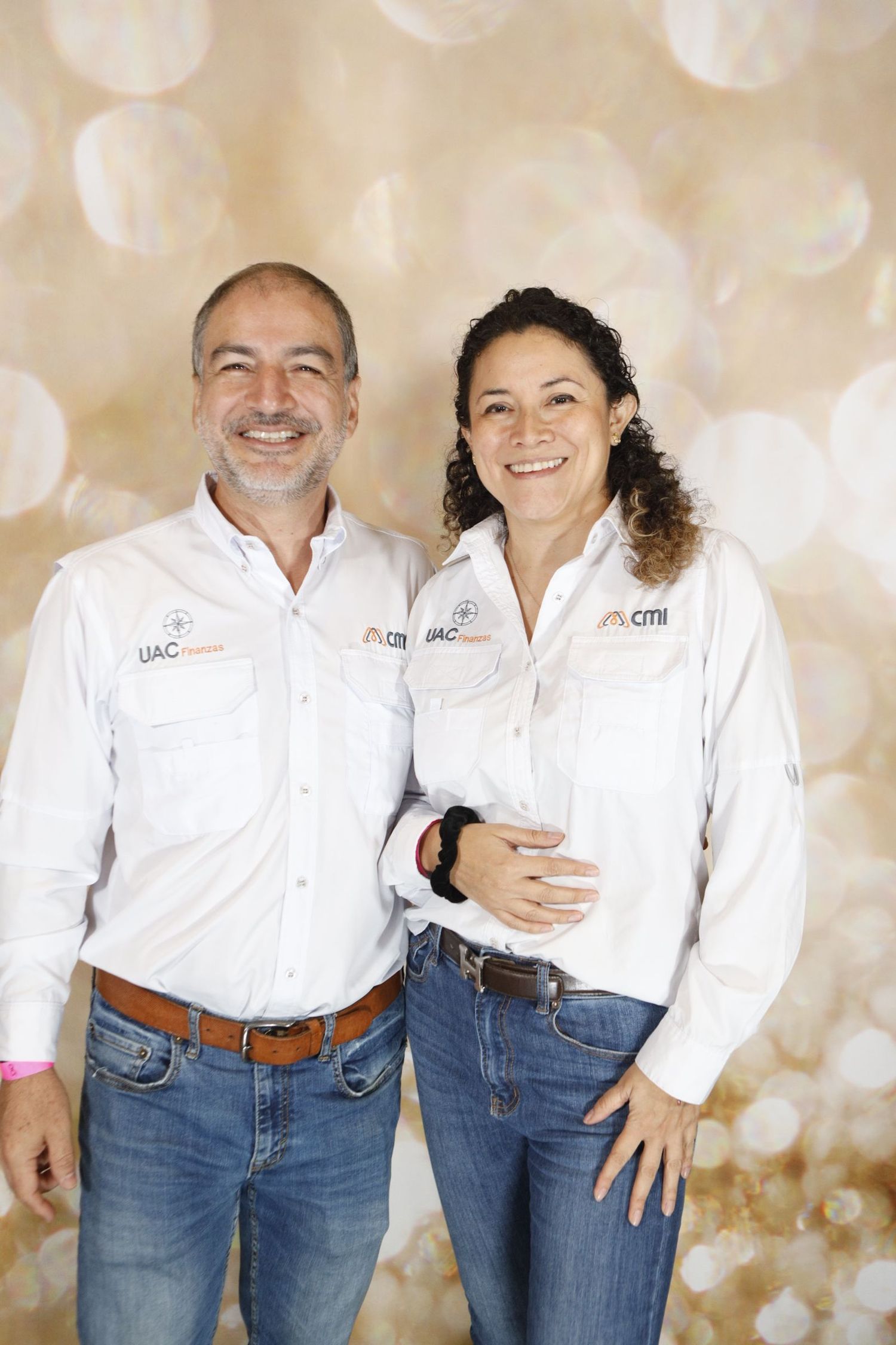 Two professionals in matching white uniforms pose together against sparkly beige background.