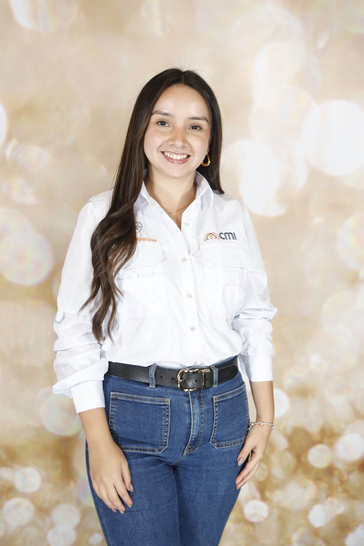Casual business portrait of someone wearing a white collared shirt and jeans against a sparkly beige backdrop.