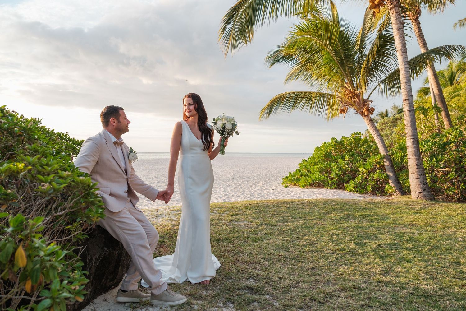 Couple shares romantic moments on sandy beach at sunset with gentle waves in background.