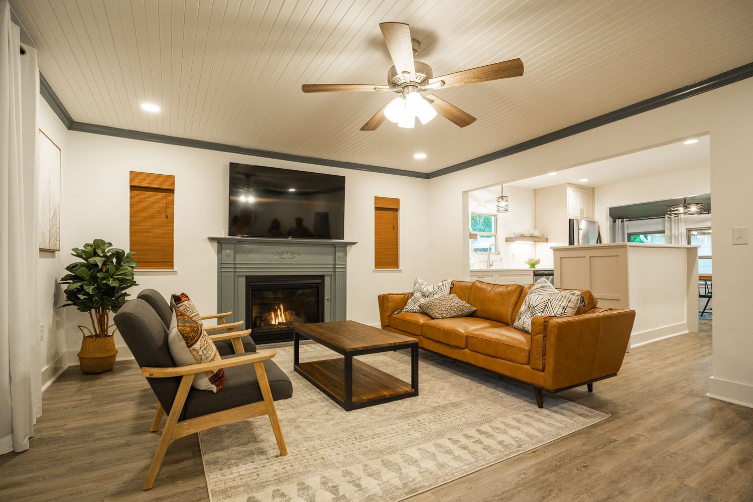 Modern basement renovation with wood paneling, tan sectional sofa, and ceiling fan in warm lighting.