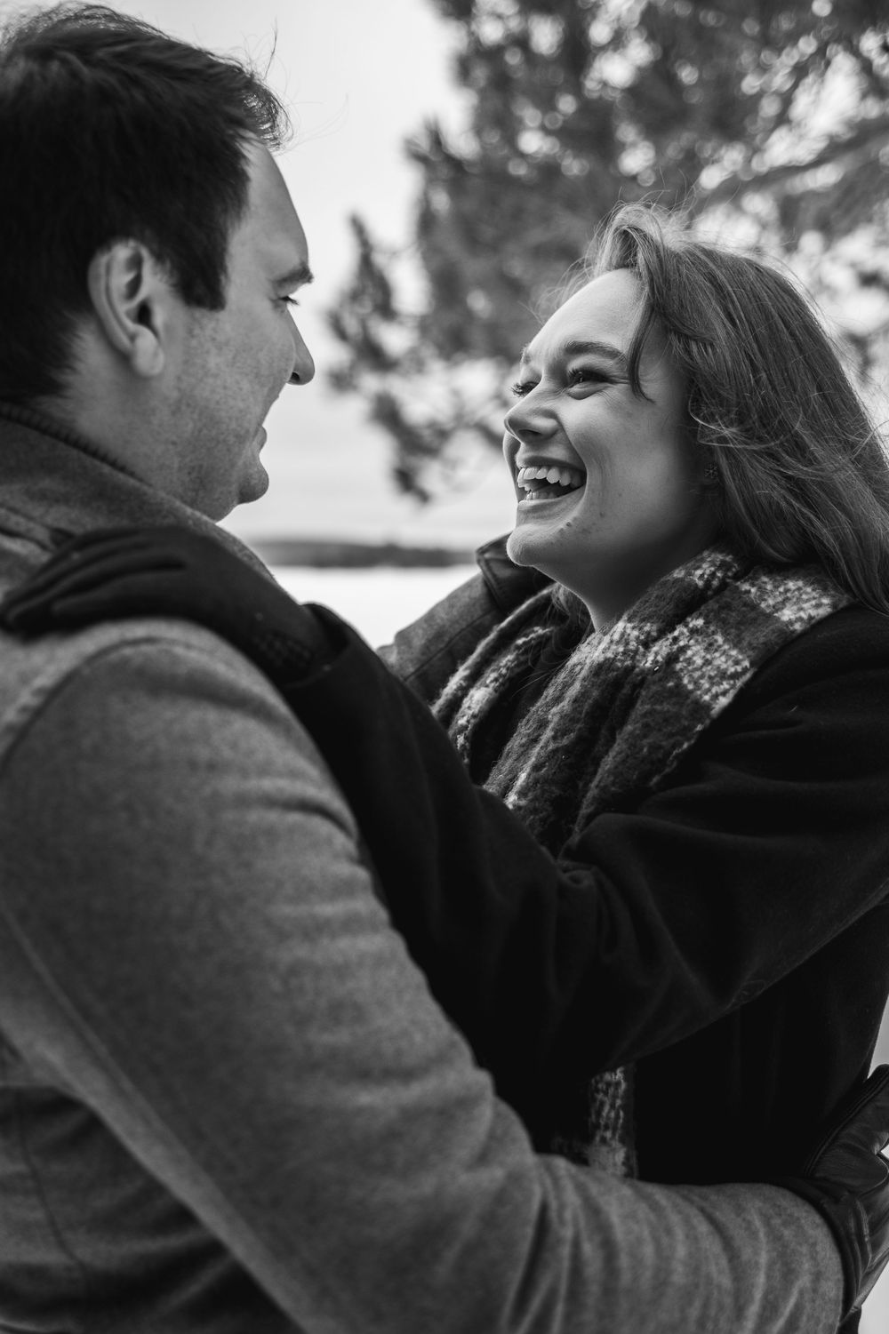 A romantic black and white portrait of a couple sharing a joyful moment together outdoors.