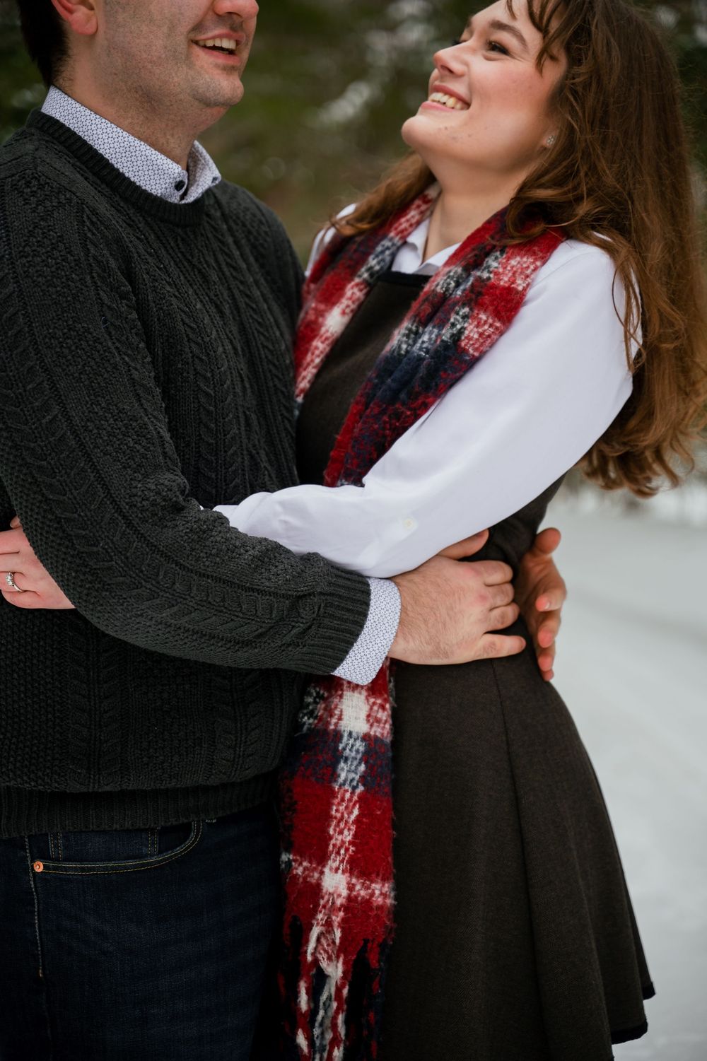 A romantic winter engagement photo series showing a couple embracing while wearing cozy sweaters and scarves.