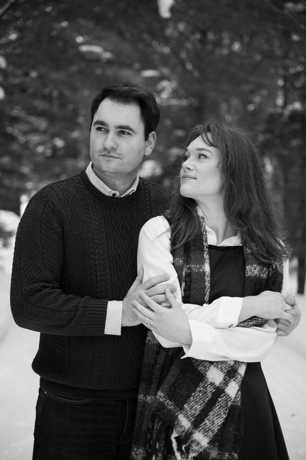 A romantic winter photoshoot featuring a couple in black sweaters sharing intimate moments in the snow.