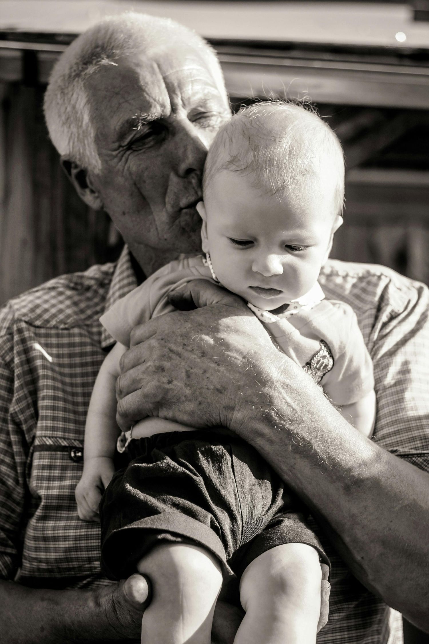 A tender black and white photo series showing a loving moment between a baby and elderly person.