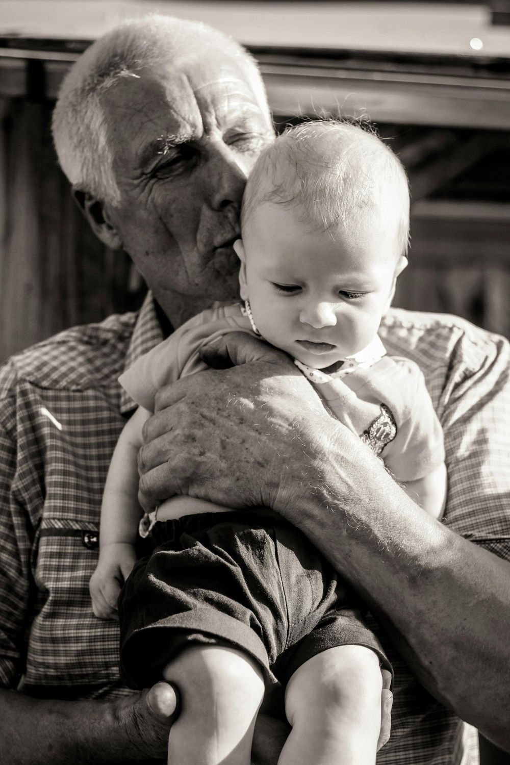 A tender black and white photo series showing a loving moment between a baby and elderly person.