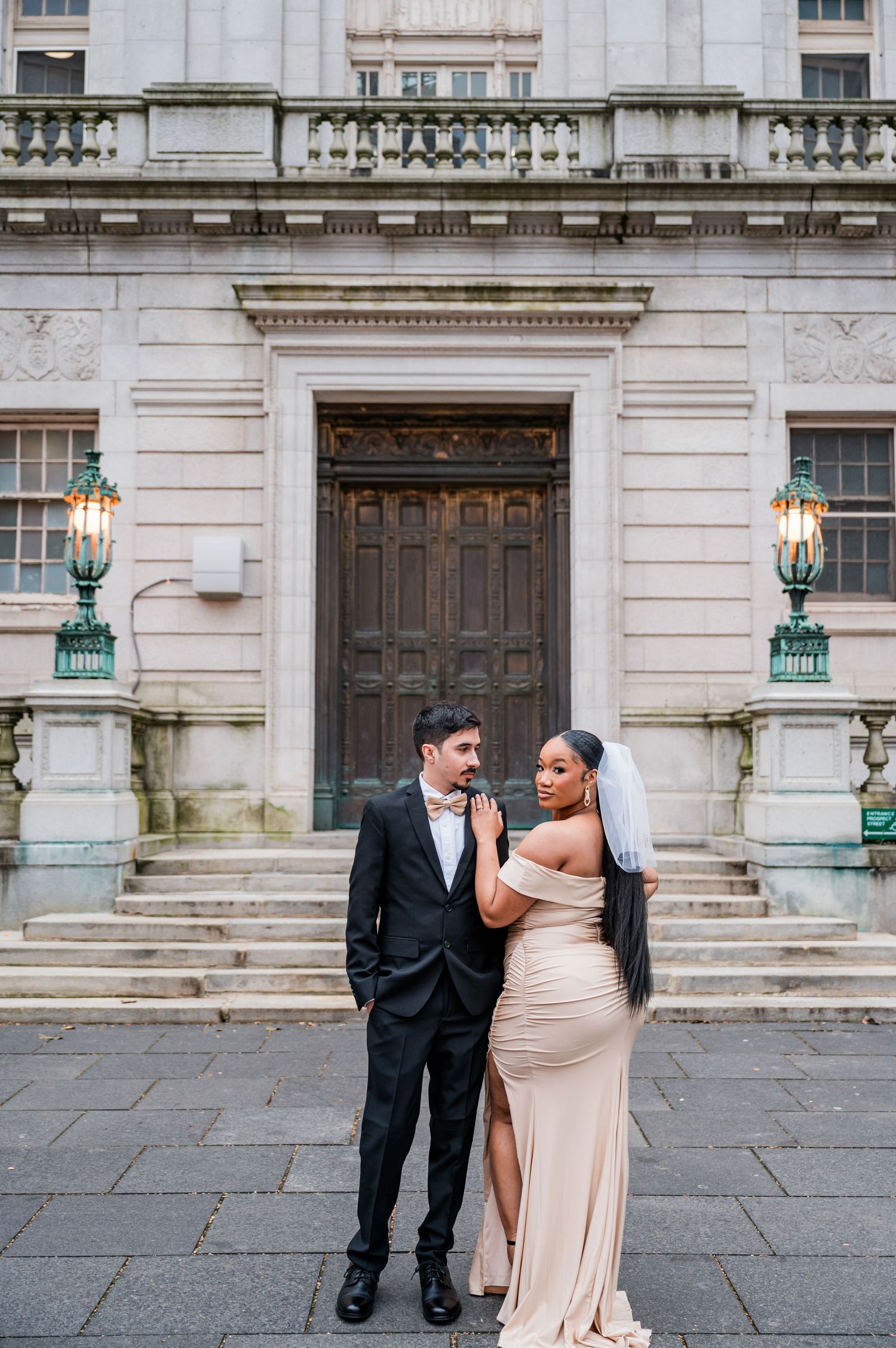 A couple in formal attire shares an intimate moment outside Hartford court house historic building with ornate architecture.
