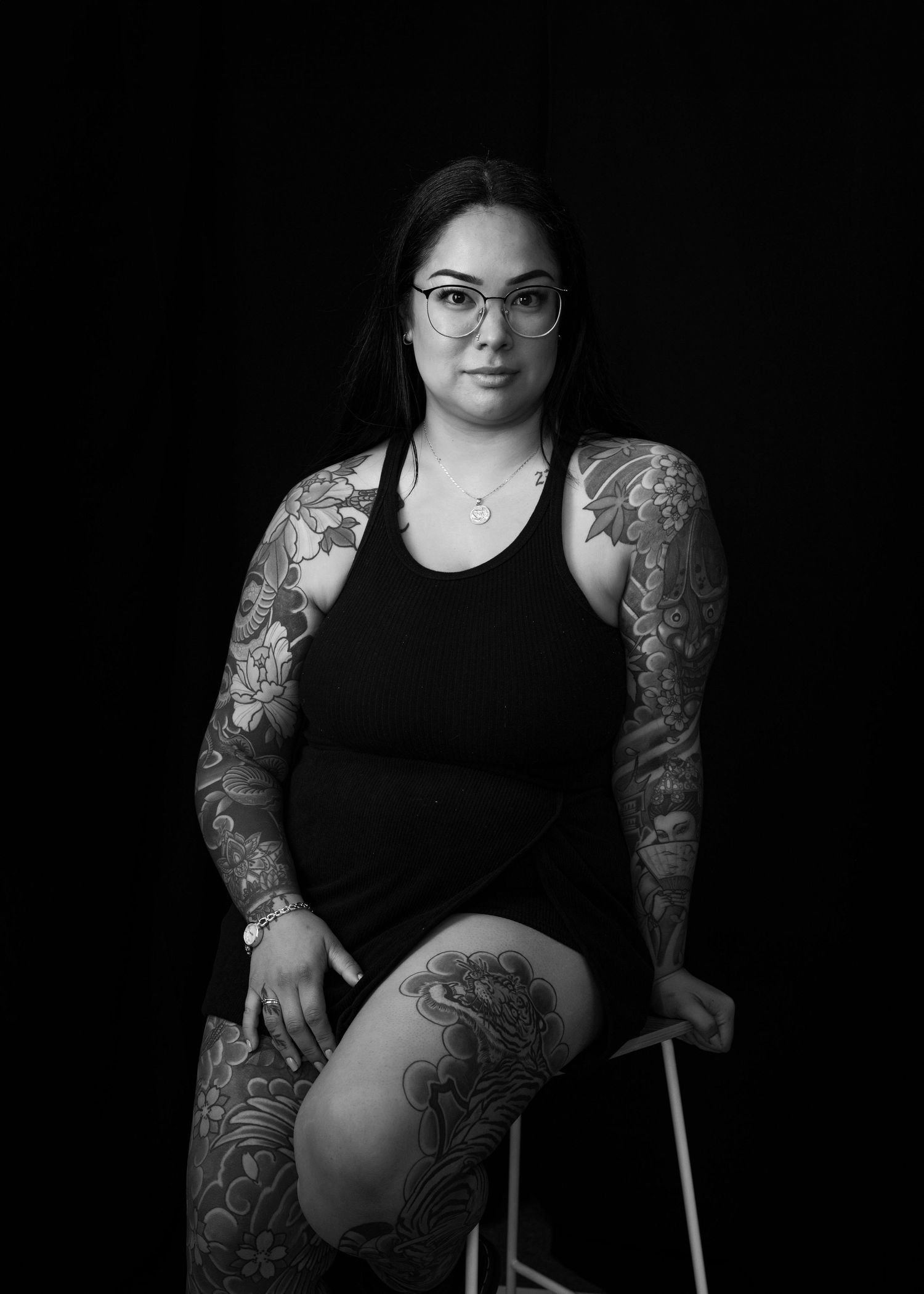 Artistic black and white portrait series showing a person in a black tank top with detailed floral sleeve tattoos.
