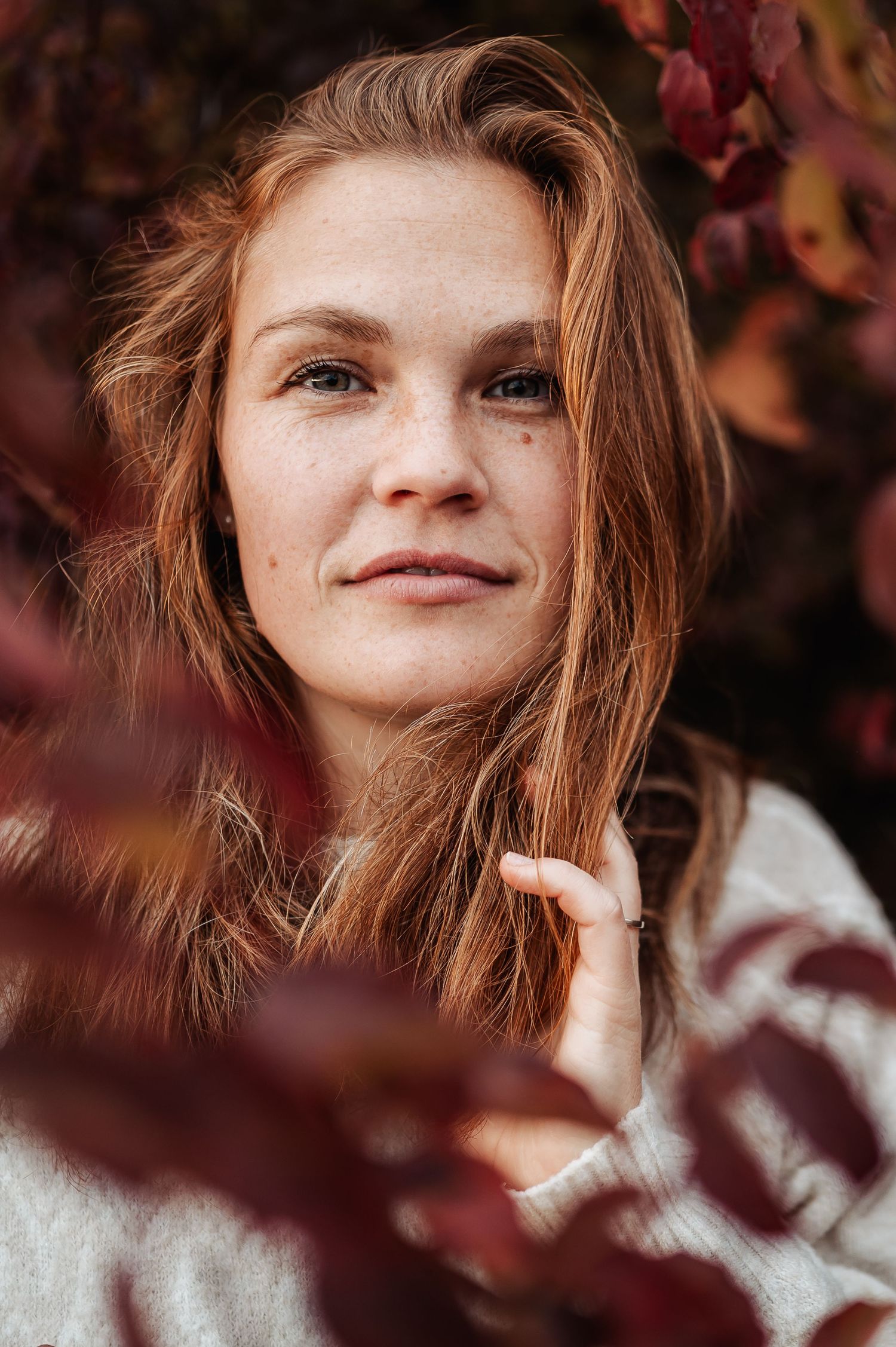 A series of close-up portraits showing someone with red hair framed by autumn leaves in soft, warm lighting.
