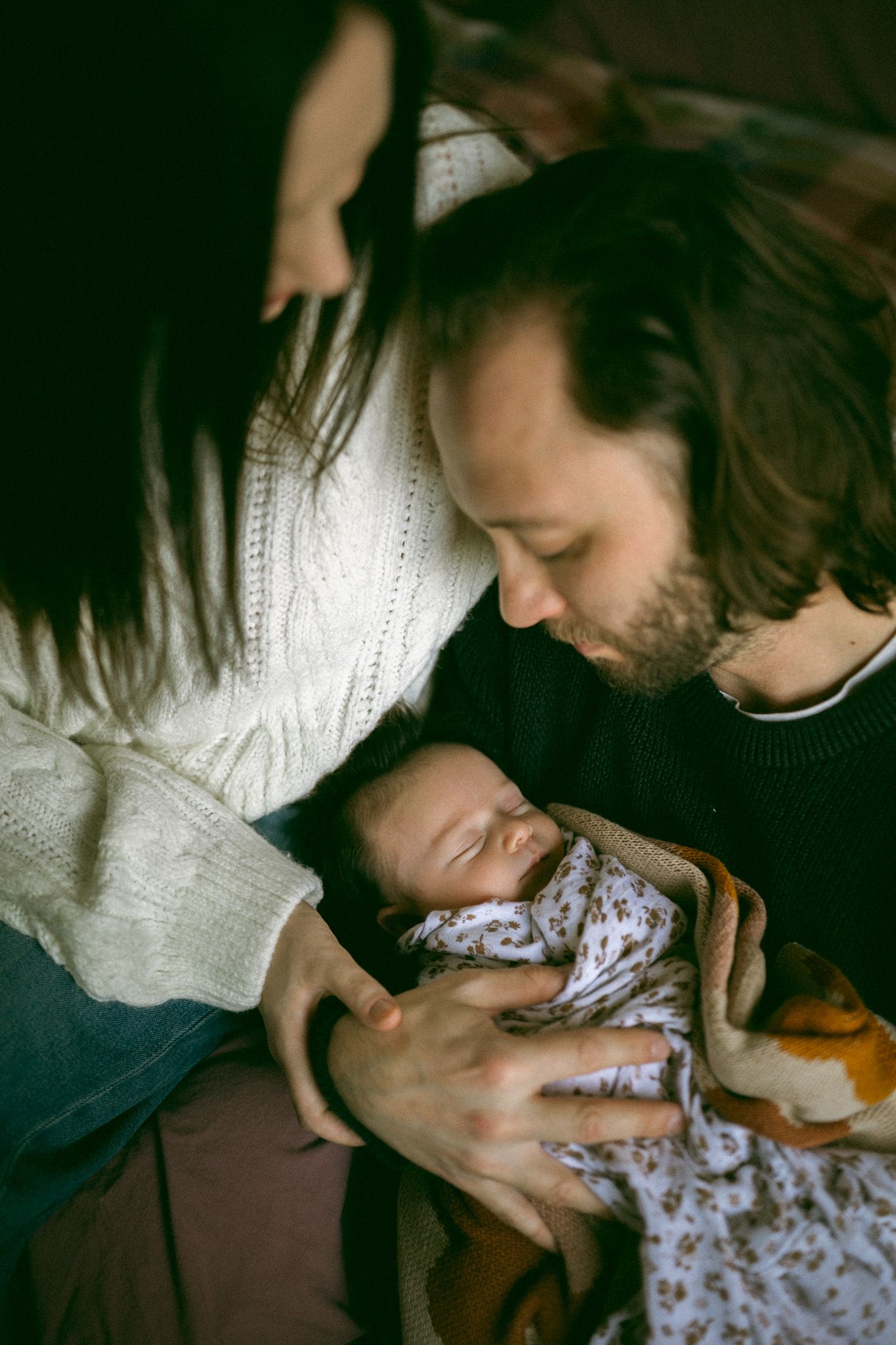 A tender moment between parent and baby in soft natural light by a window.
