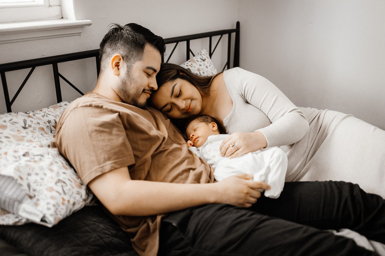 Parents snuggle their newborn on their bed in Los Gatos