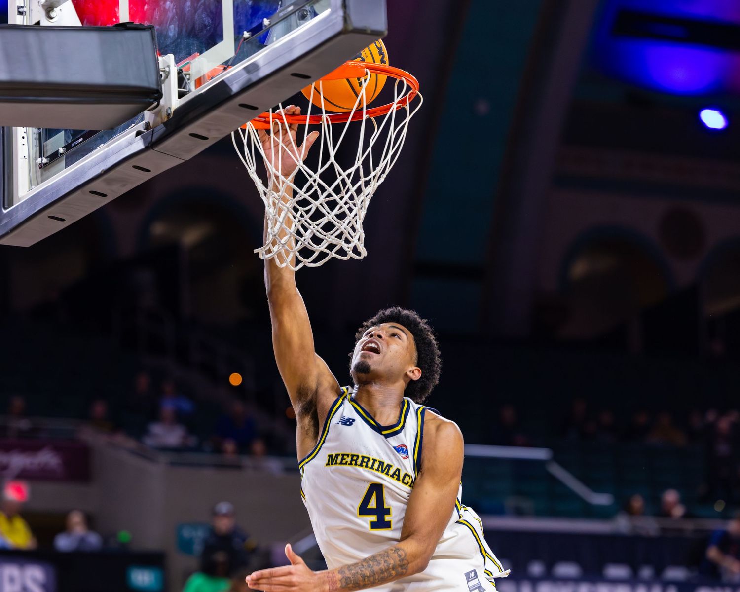 Basketball player in white jersey reaches up to score during intense game action.