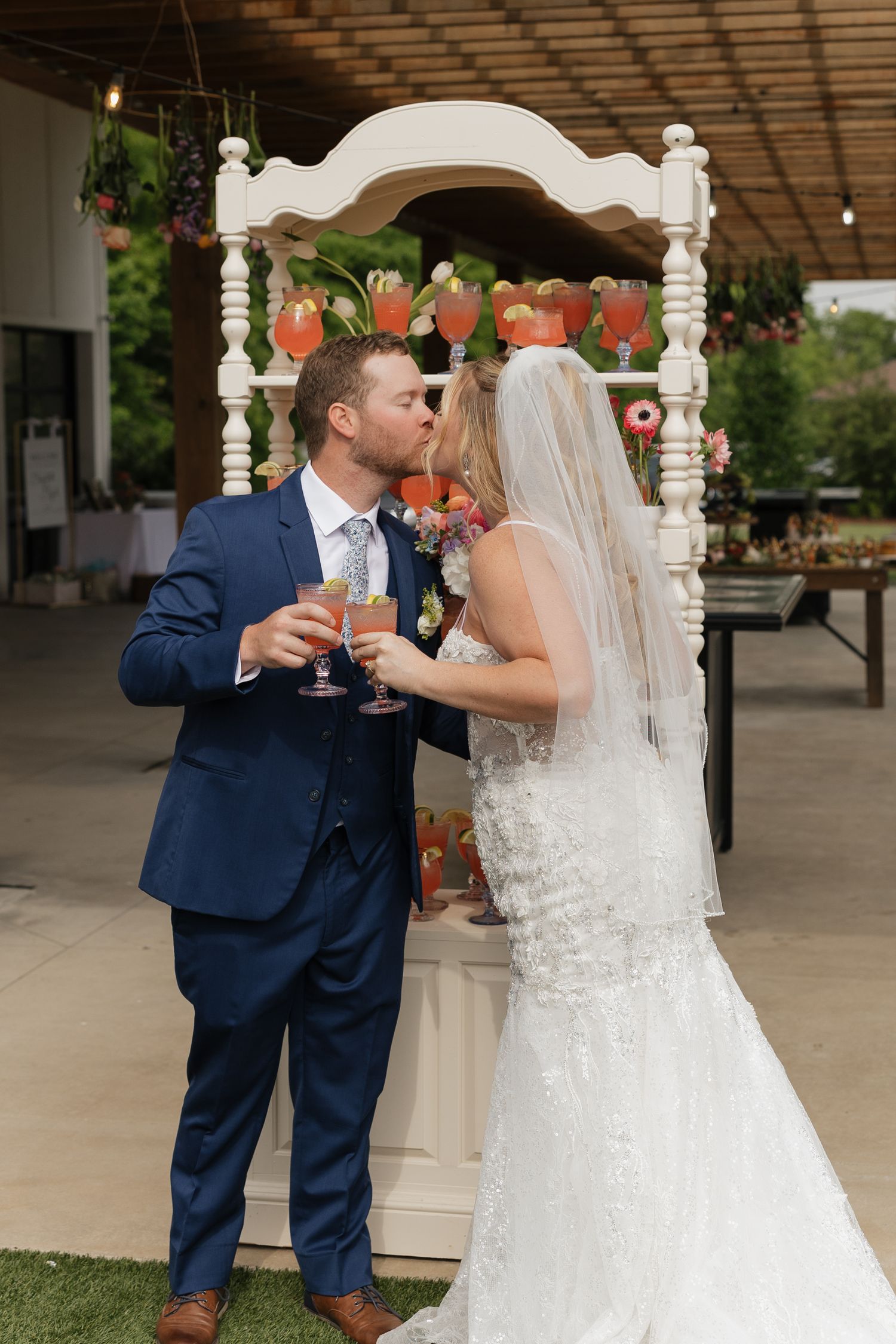 Modern rustic wedding reception venue with white tables, wooden chairs and floral arrangements in a bright airy space.
