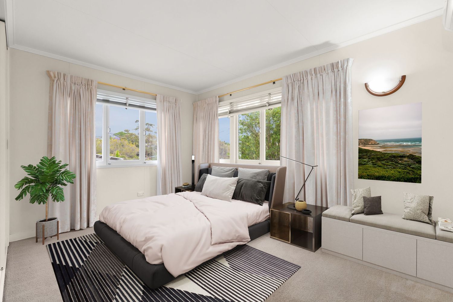 Elegant bedroom with soft pink bedding, built-in window seat, crown molding, and abundant natural light from dual windows.