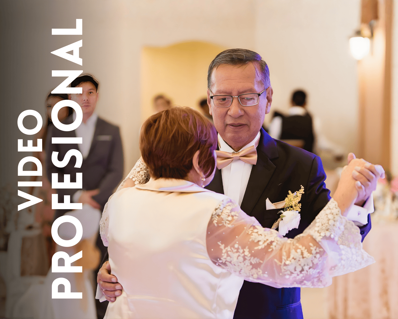 Elegant couple in formal attire dancing together at an indoor venue with white lace dress details.
