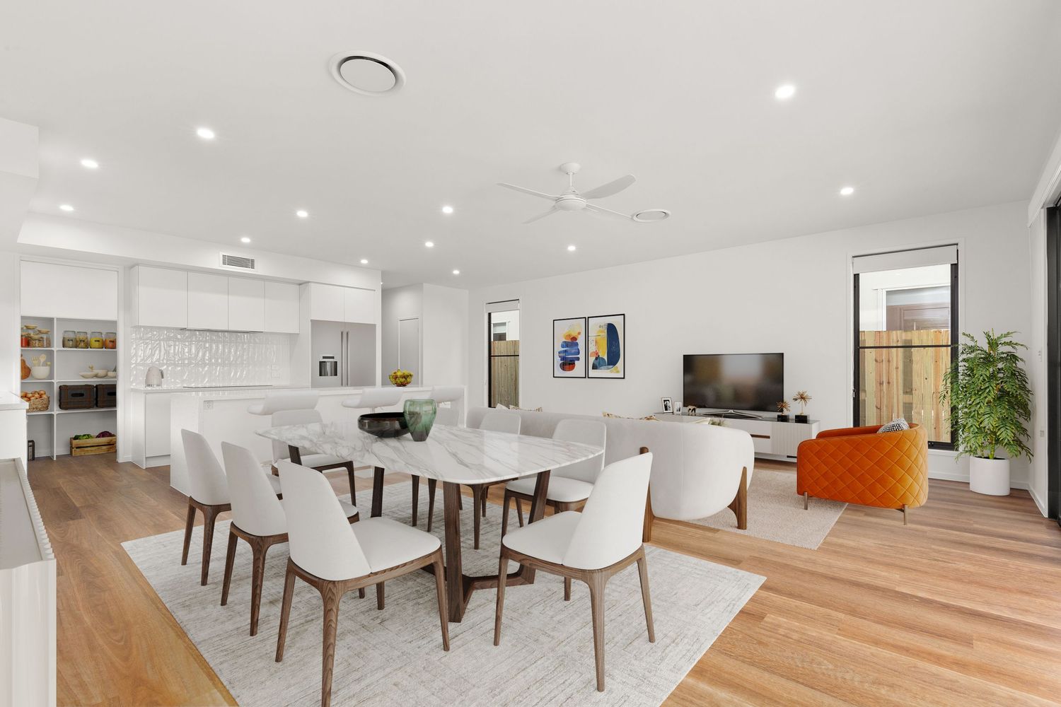 Modern open-plan dining and living area with white chairs, timber floors, black cabinetry kitchen, and ceiling fan.
