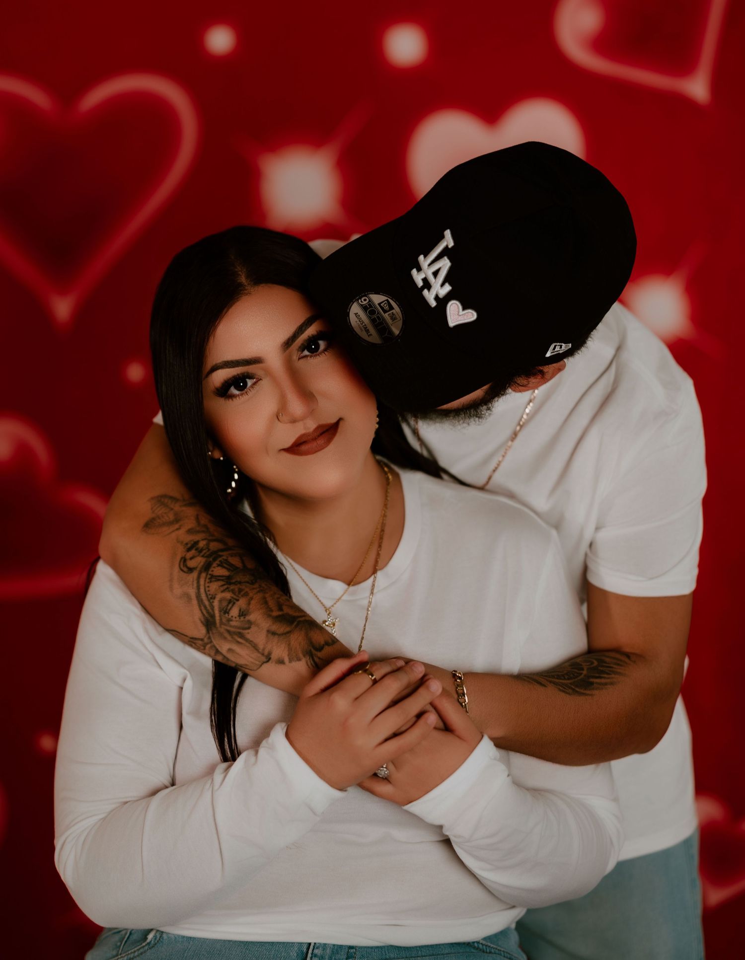 A person in a white sweater poses on red background for a moody boudoir photoshoot.