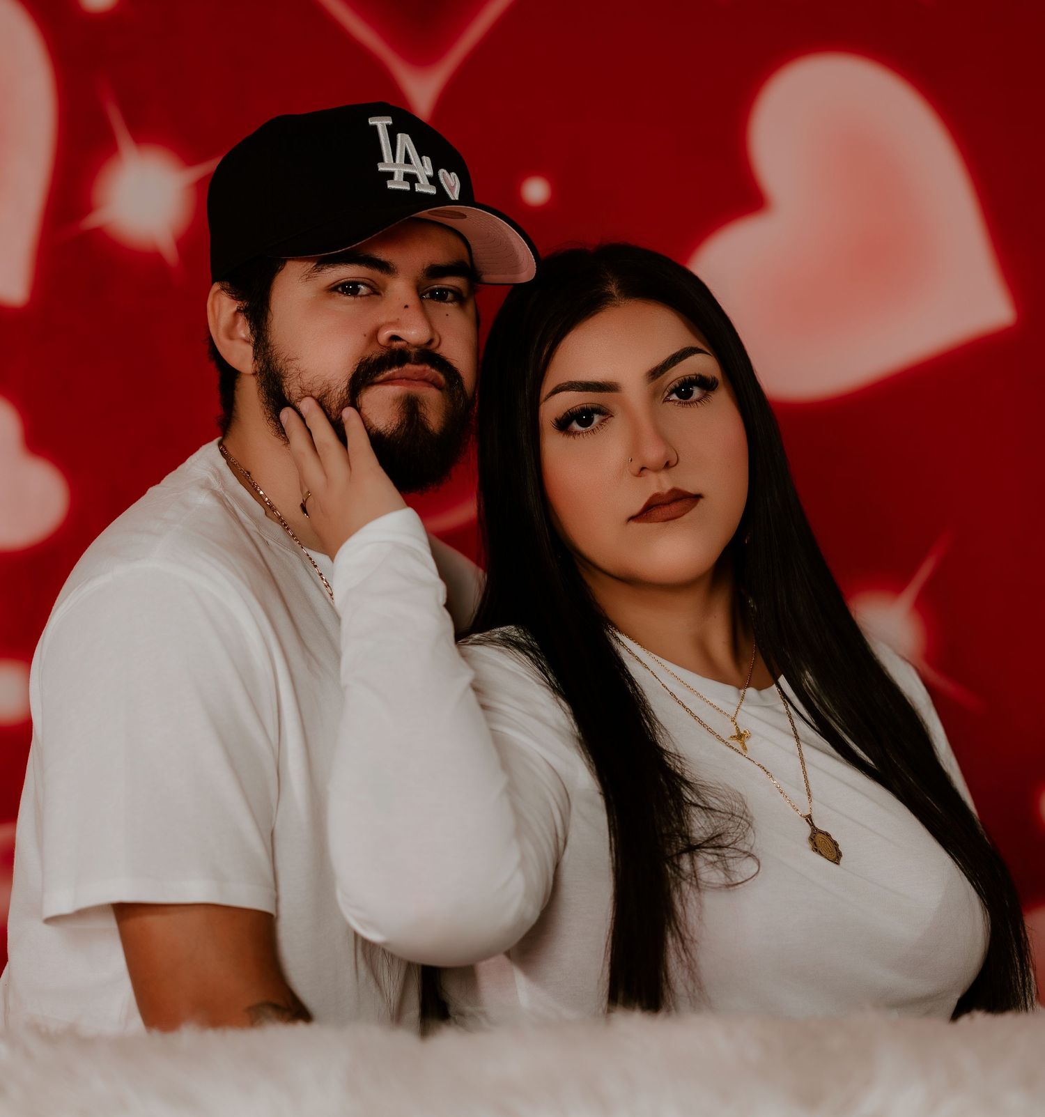 A couple in white outfits poses together against a red background in a series of romantic photos.