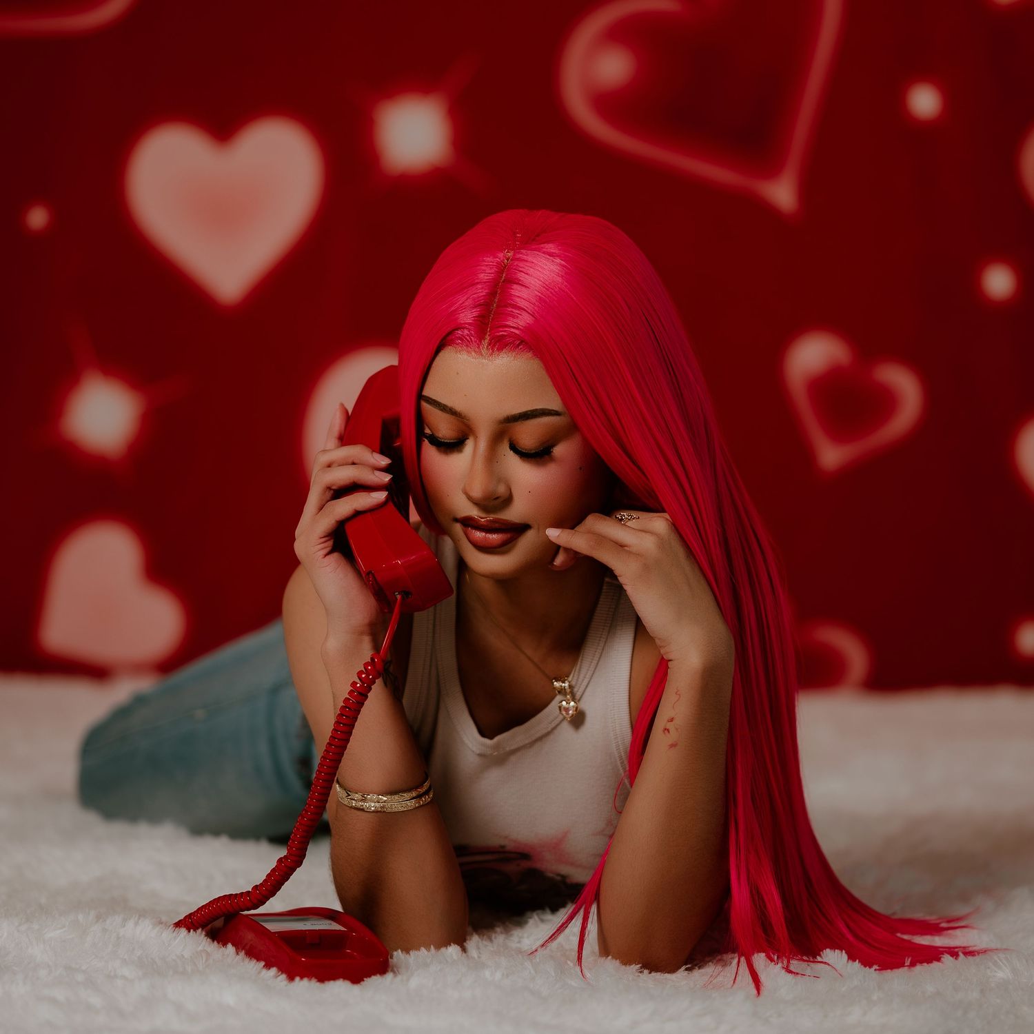 Woman with vibrant red hair lying down on white surface with heart-shaped bokeh lights in background.