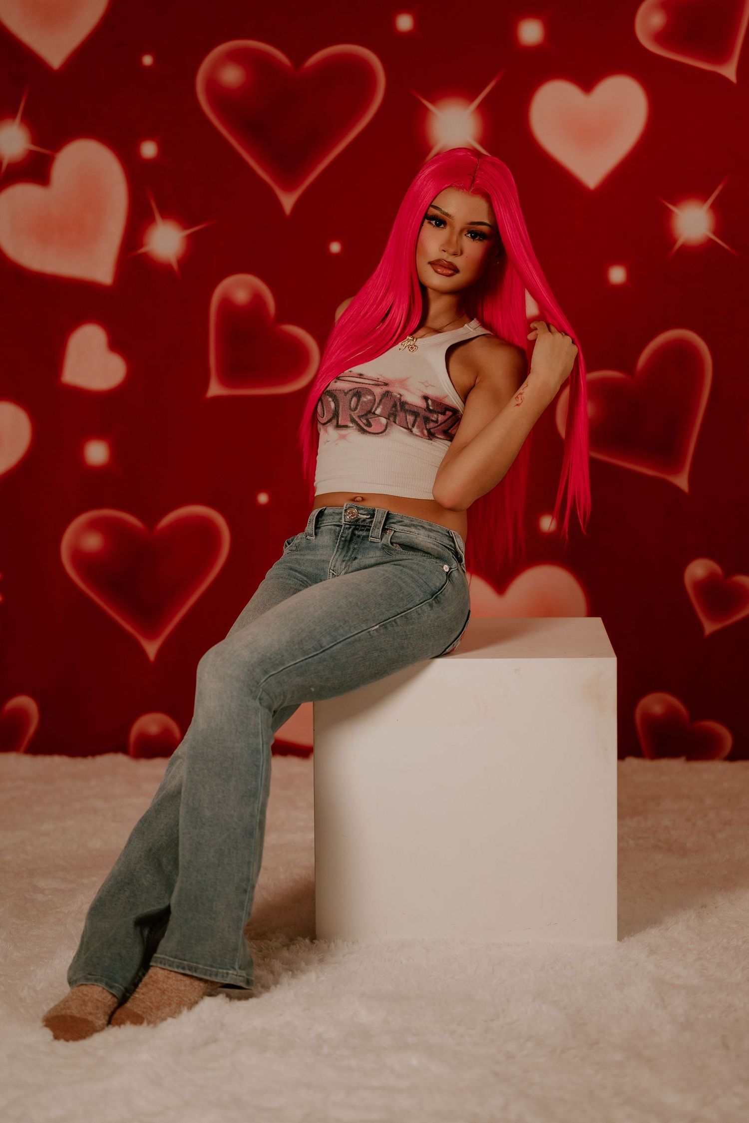 Valentine's themed photo series with red hearts background and casual denim jeans against white furniture.
