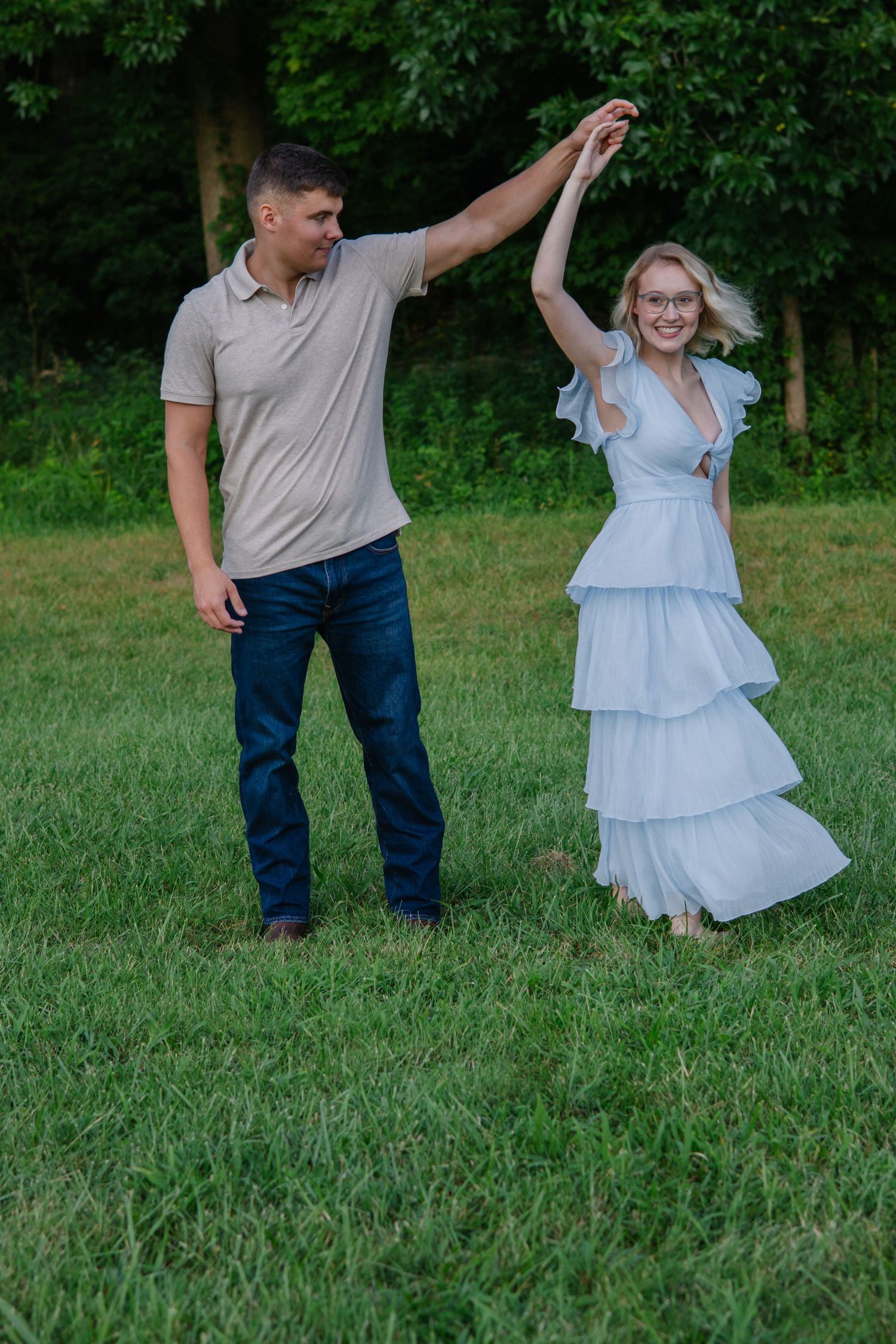 Couple dancing together on grassy field during outdoor photoshoot.