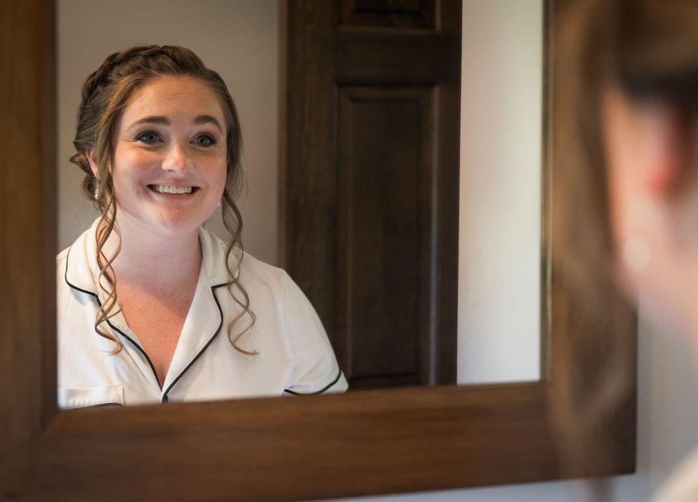Wedding preparation moments captured in soft, natural light through mirrors.