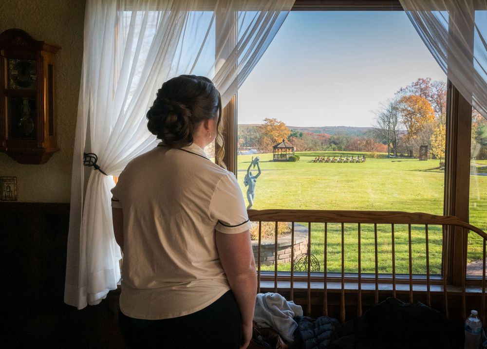 Scenic countryside view through large windows with white curtains on a sunny autumn day.