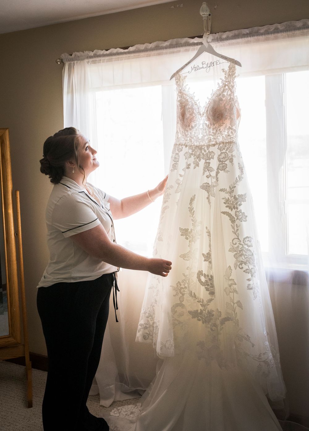 White lace wedding dress being prepared and steamed by window light.