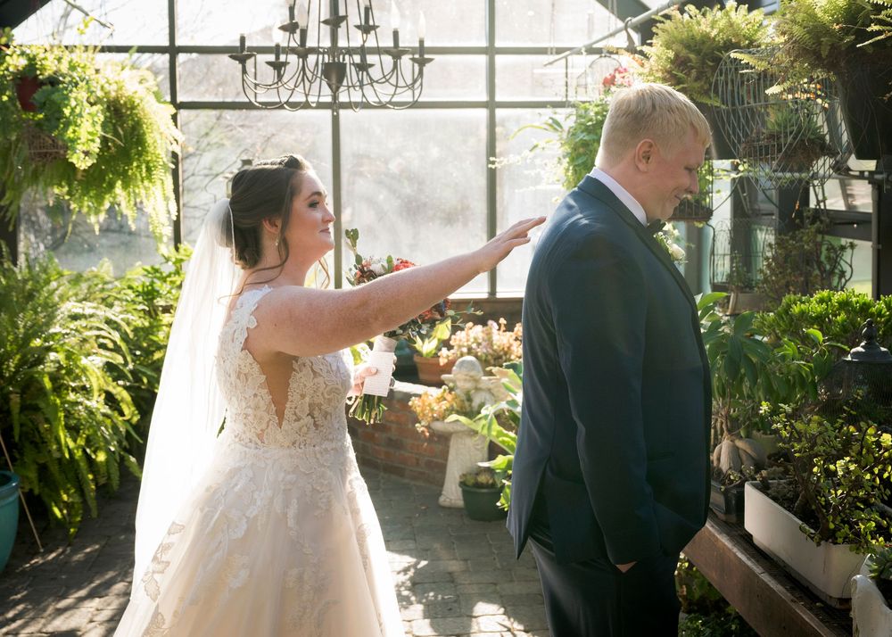 Sunlit greenhouse wedding venue with hanging plants and elegant chandeliers.